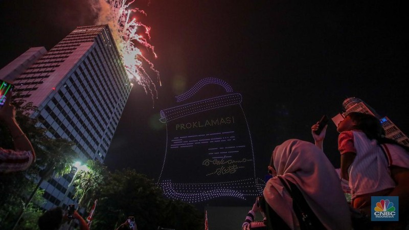 Warga menyaksikan iring-iringan karnaval saat melintas di kawasan Bundaran HI, Jakarta, Minggu (17/8/2025) malam. Acara karnaval ini menjadi pertama kalinya digelar pihak Istana dalam peringatan HUT RI. (CNBC Indonesia/Faisal Rahman)