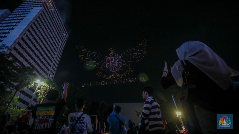 Warga menyaksikan iring-iringan karnaval saat melintas di kawasan Bundaran HI, Jakarta, Minggu (17/8/2025) malam. Acara karnaval ini menjadi pertama kalinya digelar pihak Istana dalam peringatan HUT RI. (CNBC Indonesia/Faisal Rahman)