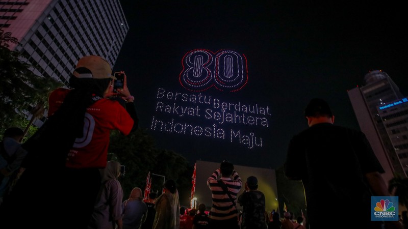 Warga menyaksikan iring-iringan karnaval saat melintas di kawasan Bundaran HI, Jakarta, Minggu (17/8/2025) malam. Acara karnaval ini menjadi pertama kalinya digelar pihak Istana dalam peringatan HUT RI. (CNBC Indonesia/Faisal Rahman)