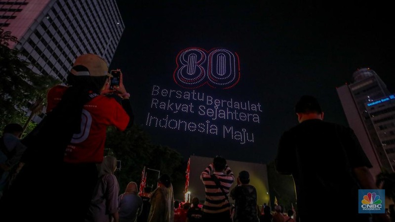 Warga menyaksikan iring-iringan karnaval saat melintas di kawasan Bundaran HI, Jakarta, Minggu (17/8/2025) malam. Acara karnaval ini menjadi pertama kalinya digelar pihak Istana dalam peringatan HUT RI. (CNBC Indonesia/Faisal Rahman)