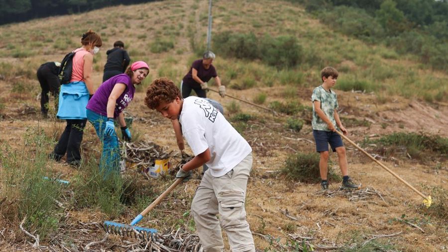 Manuel Carretero, 12, dan penduduk lainnya membersihkan semak-semak dan tumbuhan untuk mencegah kebakaran hutan mencapai desa, di Riano, dekat Leon, Spanyol, 18 Agustus 2025. (REUTERS/Nacho Doce)