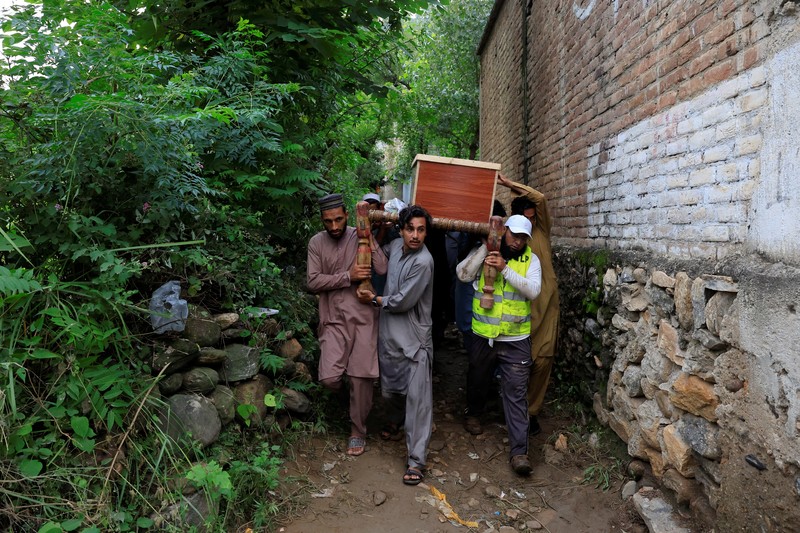 Para relawan berjalan sambil membawa payung untuk menghindari hujan saat mereka meninjau daerah yang rusak, menyusul badai yang menyebabkan hujan lebat dan banjir di Bayshonai Kalay, di distrik Buner, di provinsi Khyber Pakhtunkhwa, Pakistan, 18 Agustus 2025. (REUTERS/Akhtar Soomro)