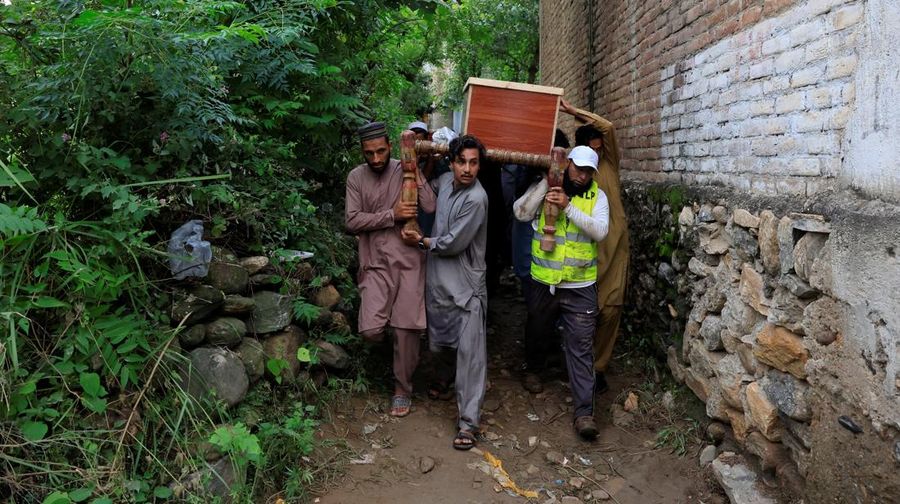 Para relawan berjalan sambil membawa payung untuk menghindari hujan saat mereka meninjau daerah yang rusak, menyusul badai yang menyebabkan hujan lebat dan banjir di Bayshonai Kalay, di distrik Buner, di provinsi Khyber Pakhtunkhwa, Pakistan, 18 Agustus 2025. (REUTERS/Akhtar Soomro)