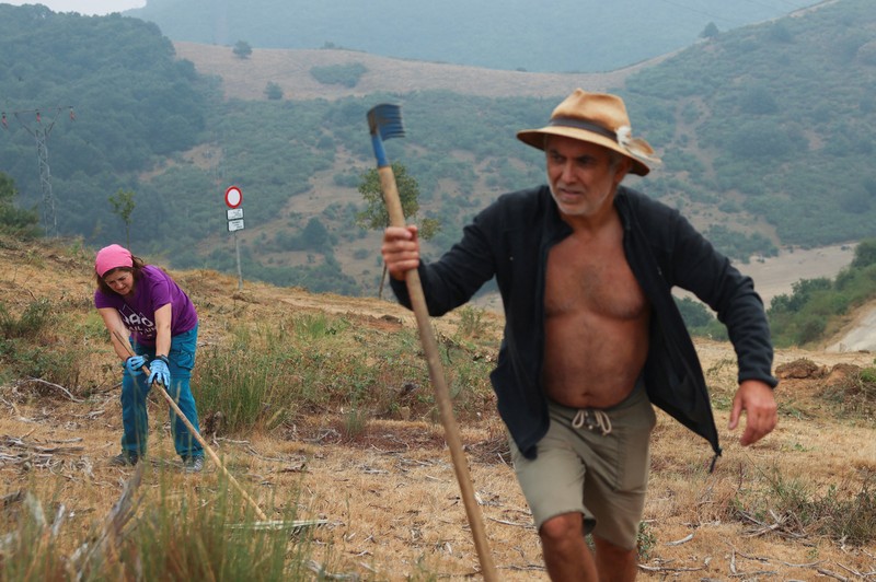 Manuel Carretero, 12, dan penduduk lainnya membersihkan semak-semak dan tumbuhan untuk mencegah kebakaran hutan mencapai desa, di Riano, dekat Leon, Spanyol, 18 Agustus 2025. (REUTERS/Nacho Doce)
