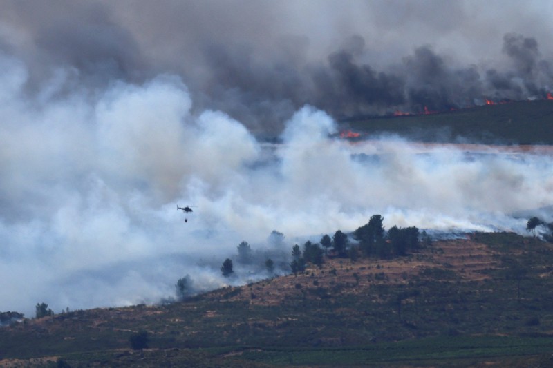 EUROPE-WEATHER/SPAIN-WILDFIRE Asap mengepul saat helikopter terbang untuk memadamkan kebakaran hutan di pegunungan Oimbra, dekat Verin, di provinsi Ourense, wilayah Galicia, Spanyol, Selasa (19/8/2025). (REUTERS/Nacho Doce)