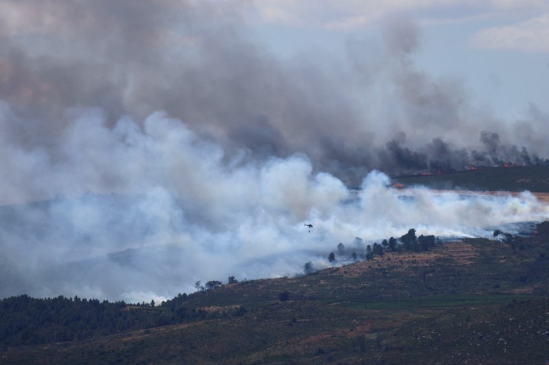 EUROPE-WEATHER/SPAIN-WILDFIRE Asap mengepul saat helikopter terbang untuk memadamkan kebakaran hutan di pegunungan Oimbra, dekat Verin, di provinsi Ourense, wilayah Galicia, Spanyol, Selasa (19/8/2025). (REUTERS/Nacho Doce)