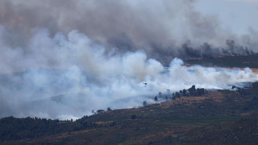 Asap mengepul saat helikopter terbang untuk memadamkan kebakaran hutan di pegunungan Oimbra, dekat Verin, di provinsi Ourense, wilayah Galicia, Spanyol, Selasa (19/8/2025). (REUTERS/Nacho Doce)