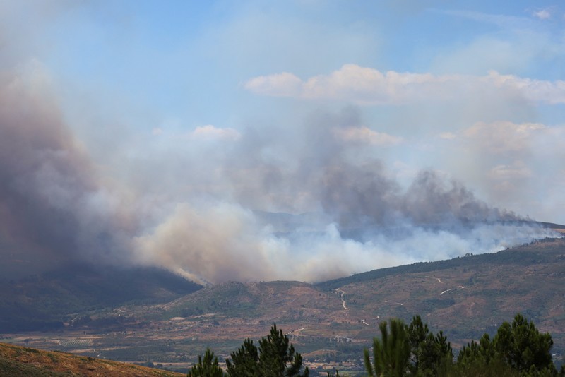 EUROPE-WEATHER/SPAIN-WILDFIRE Asap mengepul saat helikopter terbang untuk memadamkan kebakaran hutan di pegunungan Oimbra, dekat Verin, di provinsi Ourense, wilayah Galicia, Spanyol, Selasa (19/8/2025). (REUTERS/Nacho Doce)