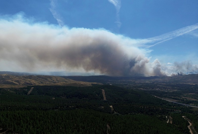 EUROPE-WEATHER/SPAIN-WILDFIRE Asap mengepul saat helikopter terbang untuk memadamkan kebakaran hutan di pegunungan Oimbra, dekat Verin, di provinsi Ourense, wilayah Galicia, Spanyol, Selasa (19/8/2025). (REUTERS/Nacho Doce)