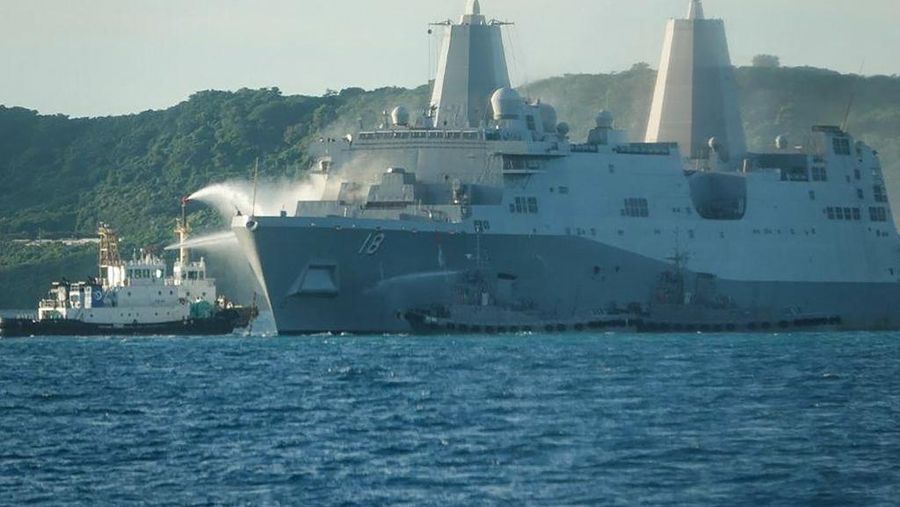 This handout photo taken on August 20, 2025 and received on August 21, 2025 from the Japan Coast Guard shows smoke coming from the US Navy vessel USS New Orleans as water is sprayed (L) to help put out the fire, off the coast near White Beach on the Japanese southern island of Okinawa. Vessels from the Coast Guard, the Japanese Self Defense Forces and private contractors have spent all night pouring water on USS New Orleans after it caught fire on August 20, the coast guard said in a statement. (Photo by Handout / Japan Coast Guard / AFP) / RESTRICTED TO EDITORIAL USE - MANDATORY CREDIT 