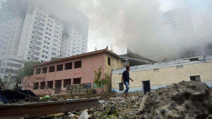 Seseorang berjalan di luar gudang kembang api saat asap mengepul setelah ledakan, di Karachi, Pakistan, 21 Agustus 2025. (REUTERS/Imran Ali)