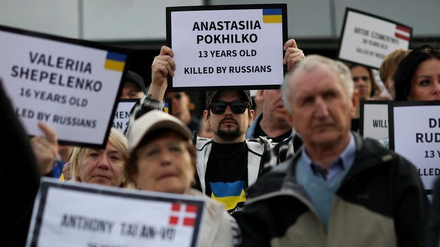 Orang-orang memegang tanda saat diaspora Ukraina berkumpul di Lapangan Kastil Warsawa untuk memperingati Hari Kemerdekaan Ukraina, di Warsawa, Polandia, 24 Agustus 2025. (REUTERS/Kacper Pempel)