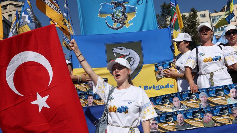Orang-orang memegang tanda saat diaspora Ukraina berkumpul di Lapangan Kastil Warsawa untuk memperingati Hari Kemerdekaan Ukraina, di Warsawa, Polandia, 24 Agustus 2025. (REUTERS/Kacper Pempel)
