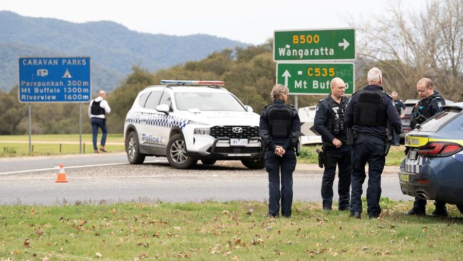 Polisi Victoria berdiri di lokasi penembakan di Porepunkah, Victoria, Australia, 26/8/2025. Sebagian kota pedesaan, termasuk sebuah sekolah dasar, telah diisolasi setelah dua petugas polisi dilaporkan ditembak mati dan seorang lainnya luka parah. AAP/Simon Dallinger via REUTERS