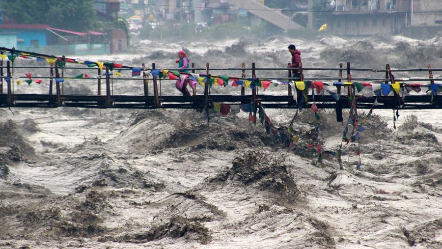 Orang-orang berjalan di jembatan untuk menyeberangi sungai Beas yang meluap setelah hujan lebat di distrik Kullu di negara bagian utara Himachal Pradesh, India, 26 Agustus 2025. (REUTERS/Aqil Khan)