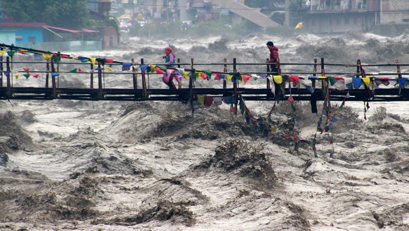 Orang-orang berjalan di jembatan untuk menyeberangi sungai Beas yang meluap setelah hujan lebat di distrik Kullu di negara bagian utara Himachal Pradesh, India, 26 Agustus 2025. (REUTERS/Aqil Khan)