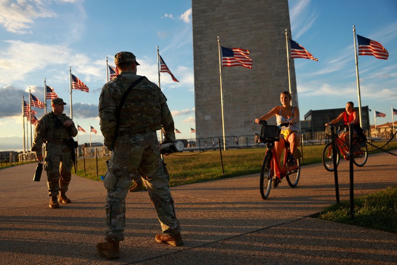 Para perempuan bersepeda saat anggota Garda Nasional, yang membawa senjata api berpatroli di National Mall, beberapa minggu setelah Presiden AS Donald Trump memerintahkan Garda Nasional dan penegak hukum untuk berpatroli di ibu kota negara guna membantu pencegahan kejahatan, di Washington, D.C., AS, 26 Agustus 2025. Para perempuan bersepeda saat anggota Garda Nasional, yang membawa senjata api berpatroli di National Mall, beberapa minggu setelah Presiden AS Donald Trump memerintahkan Garda Nasional dan penegak hukum untuk berpatroli di ibu kota negara guna membantu pencegahan kejahatan, di Washington, D.C., AS, 26 Agustus 2025. (REUTERS/Jose Luis Gonzalez)