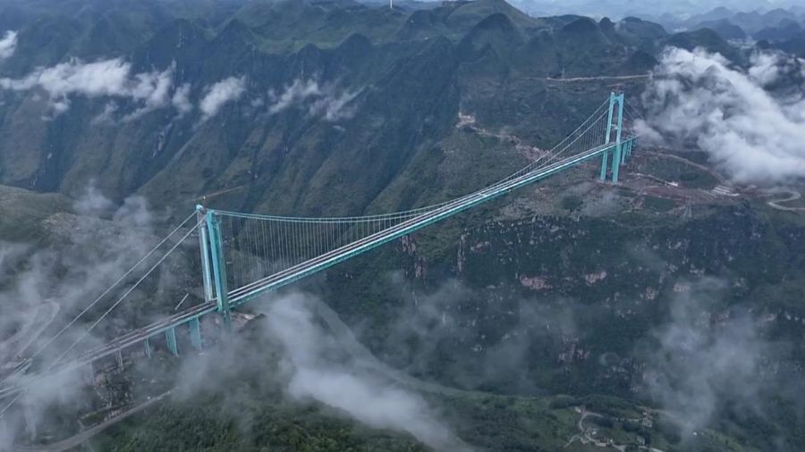 Jembatan Huajiang Grand Canyon di Provinsi Guizhou, Tiongkok barat daya, yang ditetapkan sebagai jembatan tertinggi di dunia, menyelesaikan uji beban utama pada hari Senin, menjelang pembukaan yang dijadwalkan pada akhir September. (Tangkapan Layar China Central Television via Reuters)