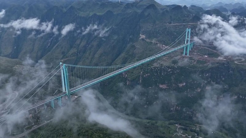 Jembatan Huajiang Grand Canyon di Provinsi Guizhou, Tiongkok barat daya, yang ditetapkan sebagai jembatan tertinggi di dunia, menyelesaikan uji beban utama pada hari Senin, menjelang pembukaan yang dijadwalkan pada akhir September. (Tangkapan Layar China Central Television via Reuters)