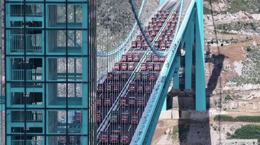 Jembatan Huajiang Grand Canyon di Provinsi Guizhou, Tiongkok barat daya, yang ditetapkan sebagai jembatan tertinggi di dunia, menyelesaikan uji beban utama pada hari Senin, menjelang pembukaan yang dijadwalkan pada akhir September. (Tangkapan Layar China Central Television via Reuters)