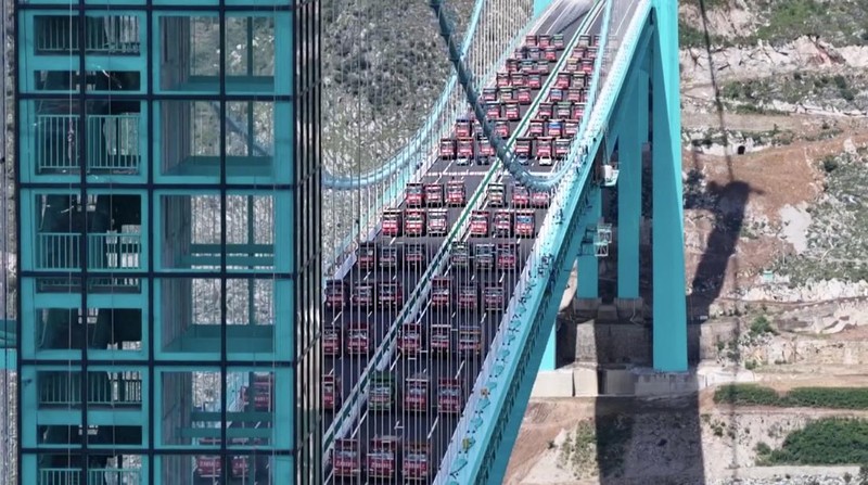 Jembatan Huajiang Grand Canyon di Provinsi Guizhou, Tiongkok barat daya, yang ditetapkan sebagai jembatan tertinggi di dunia, menyelesaikan uji beban utama pada hari Senin, menjelang pembukaan yang dijadwalkan pada akhir September. (Tangkapan Layar China Central Television via Reuters)