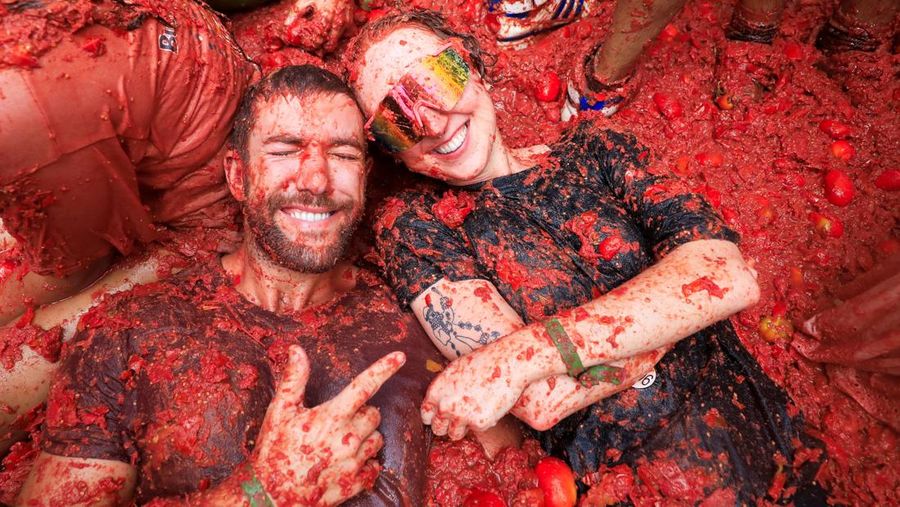 Para pengunjung yang bersuka ria bermain dengan bubur tomat selama festival perang makanan tahunan 'La Tomatina' di Bunol, dekat Valencia, Spanyol, 27 Agustus 2025. (REUTERS/Eva Manez)
