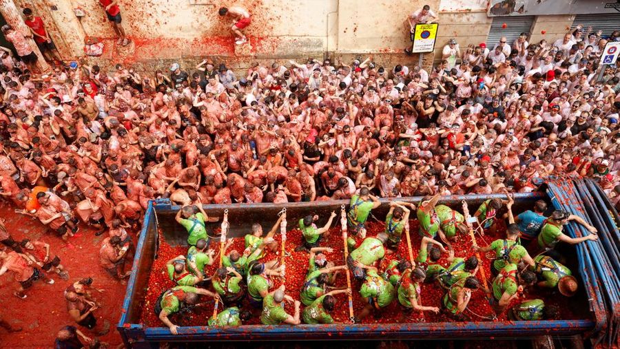 Para pengunjung yang bersuka ria bermain dengan bubur tomat selama festival perang makanan tahunan 'La Tomatina' di Bunol, dekat Valencia, Spanyol, 27 Agustus 2025. (REUTERS/Eva Manez)