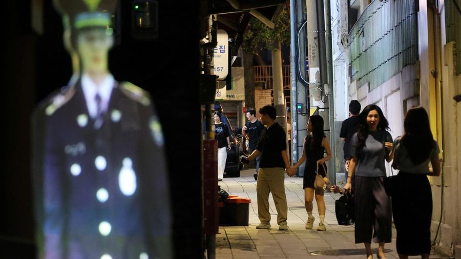 People walk near a life-size holographic police officer installed to prevent crime at a park in Seoul, South Korea, August 28, 2025. REUTERS/Kim Hong-Ji