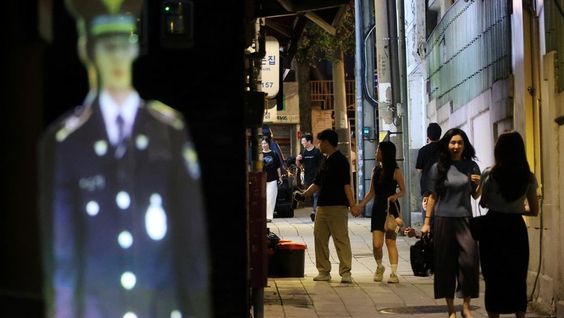 People walk near a life-size holographic police officer installed to prevent crime at a park in Seoul, South Korea, August 28, 2025. REUTERS/Kim Hong-Ji