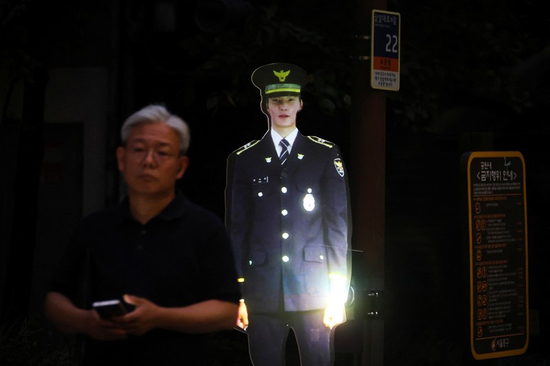 SOUTHKOREA-SECURITY/HOLOGRAM POLICE People walk near a life-size holographic police officer installed to prevent crime at a park in Seoul, South Korea, August 28, 2025. REUTERS/Kim Hong-Ji