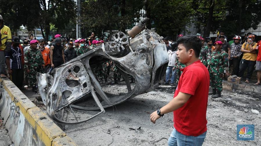 Warga mengambil sisa-sisa besi dari mobil yang hangus terbakar saat aksi di kawasan Mako Brimob Kwitang, Jakarta, Jumat (29/8/2025). (CNBC Indonesia/Tri Susilo)