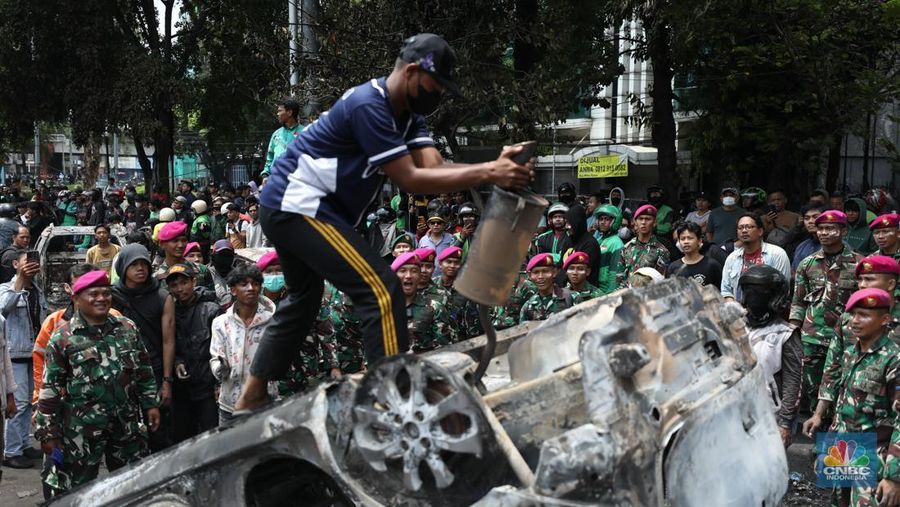 Warga mengambil sisa-sisa besi dari mobil yang hangus terbakar saat aksi di kawasan Mako Brimob Kwitang, Jakarta, Jumat (29/8/2025). (CNBC Indonesia/Tri Susilo)