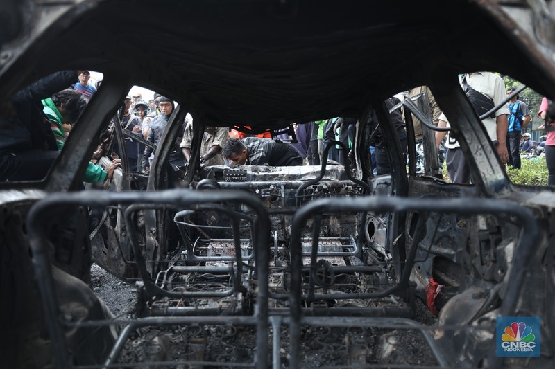 Warga mengambil sisa-sisa besi dari mobil yang hangus terbakar saat aksi di kawasan Mako Brimob Kwitang, Jakarta, Jumat (29/8/2025). (CNBC Indonesia/Tri Susilo)