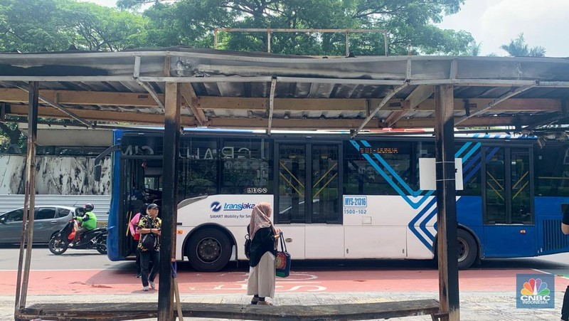 Sejumlah penumpang masih menggunakan halte TransJakarta Senayan Bank DKI, Jakarta, Senin (1/9/2025) usai terbakar pasca demonstrasi.  (CNBC Indonesia/Fergi Nadira)