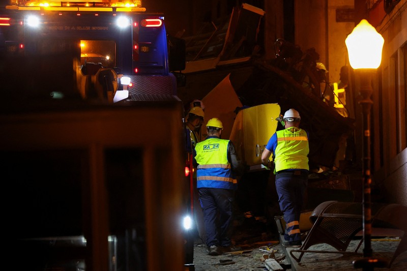 Para pekerja mengangkat puing-puing kereta gantung Ascensor da Glória di Lisbon, Portugal, Jumat (5/9/2025). (REUTERS/Pedro Nunes) Para pekerja mengangkat puing-puing kereta gantung Ascensor da Glória di Lisbon, Portugal, Jumat (5/9/2025). (REUTERS/Pedro Nunes)