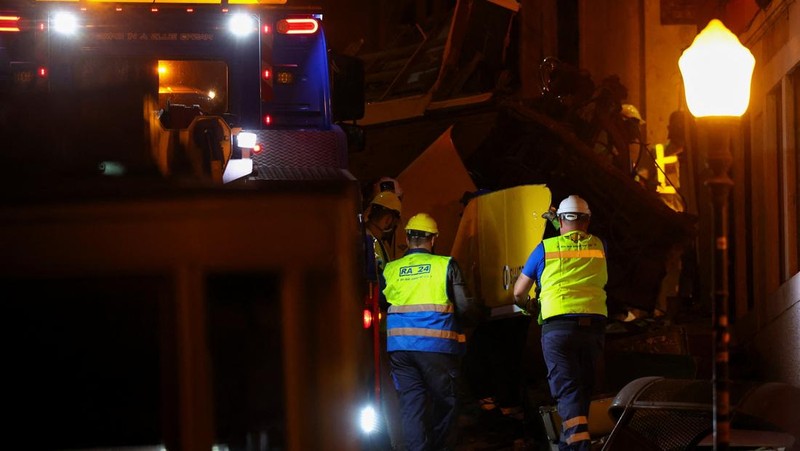 Para pekerja mengangkat puing-puing kereta gantung Ascensor da Glória di Lisbon, Portugal, Jumat (5/9/2025). (REUTERS/Pedro Nunes)