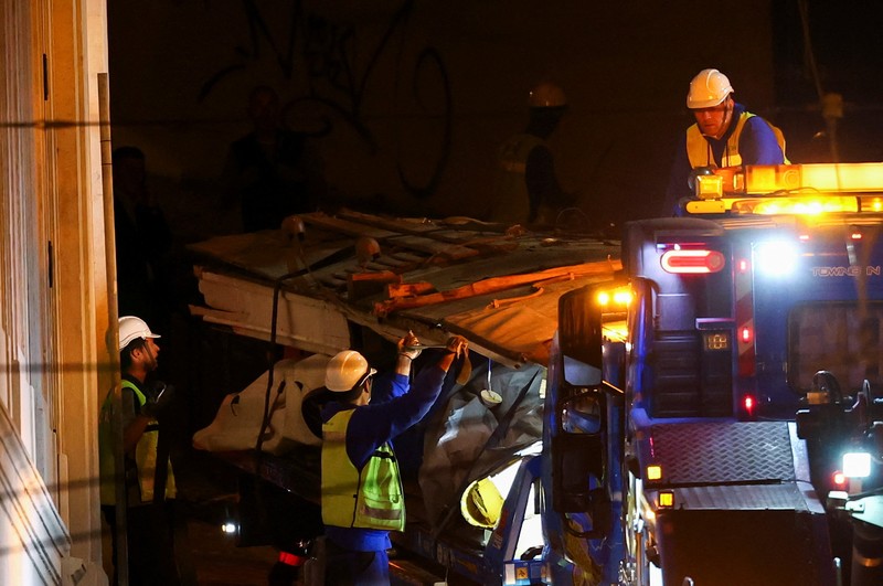 Para pekerja mengangkat puing-puing kereta gantung Ascensor da Glória di Lisbon, Portugal, Jumat (5/9/2025). (REUTERS/Pedro Nunes)