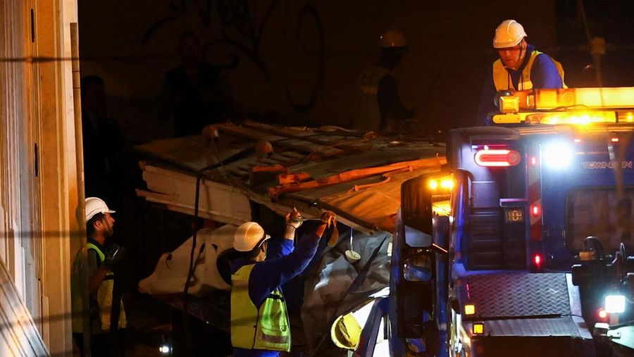 Para pekerja mengangkat puing-puing kereta gantung Ascensor da Glória di Lisbon, Portugal, Jumat (5/9/2025). (REUTERS/Pedro Nunes)