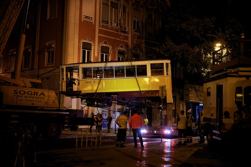 Para pekerja mengangkat puing-puing kereta gantung Ascensor da Glória di Lisbon, Portugal, Jumat (5/9/2025). (REUTERS/Pedro Nunes) Para pekerja mengangkat puing-puing kereta gantung Ascensor da Glória di Lisbon, Portugal, Jumat (5/9/2025). (REUTERS/Pedro Nunes)
