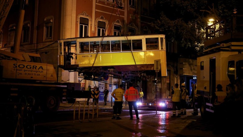 Para pekerja mengangkat puing-puing kereta gantung Ascensor da Glória di Lisbon, Portugal, Jumat (5/9/2025). (REUTERS/Pedro Nunes)