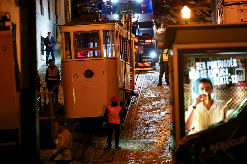 Para pekerja mengangkat puing-puing kereta gantung Ascensor da Glória di Lisbon, Portugal, Jumat (5/9/2025). (REUTERS/Pedro Nunes)