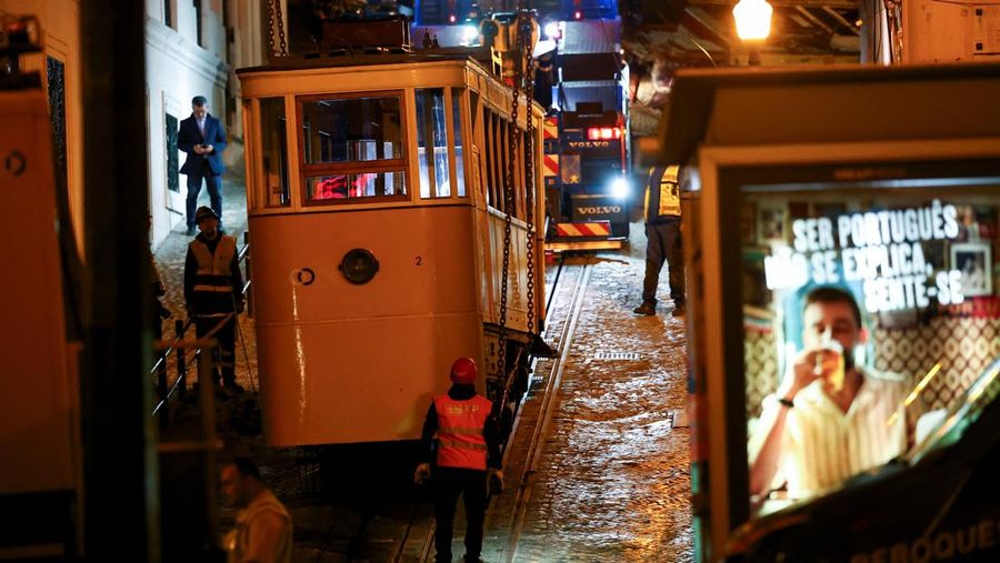 Para pekerja mengangkat puing-puing kereta gantung Ascensor da Glória di Lisbon, Portugal, Jumat (5/9/2025). (REUTERS/Pedro Nunes)