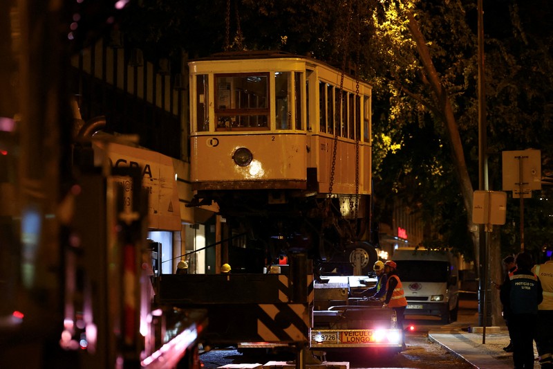 Para pekerja mengangkat puing-puing kereta gantung Ascensor da Glória di Lisbon, Portugal, Jumat (5/9/2025). (REUTERS/Pedro Nunes) Para pekerja mengangkat puing-puing kereta gantung Ascensor da Glória di Lisbon, Portugal, Jumat (5/9/2025). (REUTERS/Pedro Nunes)