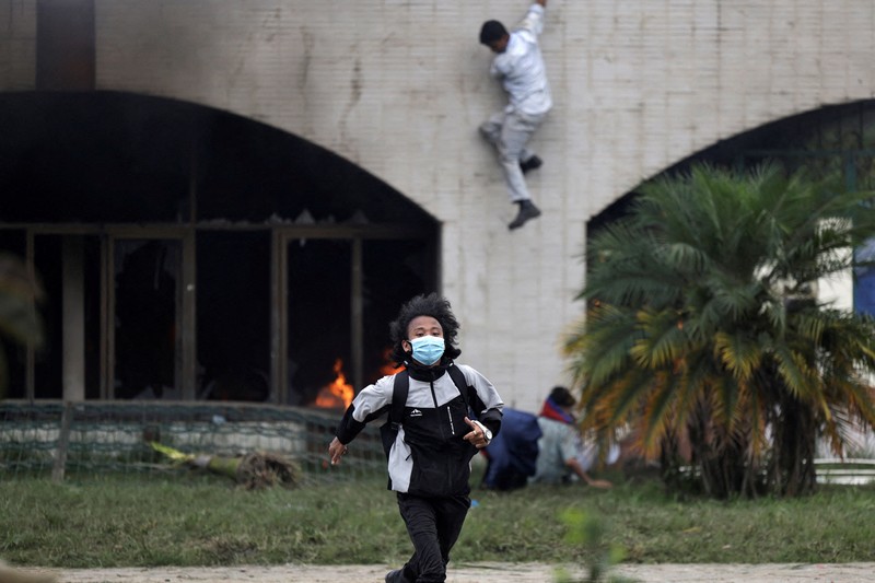 Smoke billows from an ambulance next to riot police officers and demonstrators during a protest against corruption and the government’s decision to block several social media platforms, in Kathmandu, Nepal September 8, 2025. REUTERS/Stringer