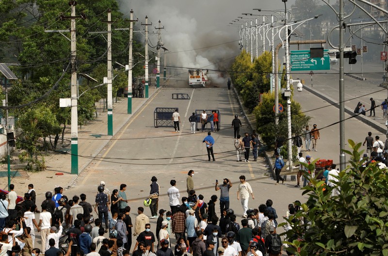 Smoke billows from an ambulance next to riot police officers and demonstrators during a protest against corruption and the government’s decision to block several social media platforms, in Kathmandu, Nepal September 8, 2025. REUTERS/Stringer