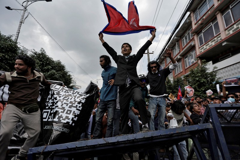 Smoke billows from an ambulance next to riot police officers and demonstrators during a protest against corruption and the government’s decision to block several social media platforms, in Kathmandu, Nepal September 8, 2025. REUTERS/Stringer