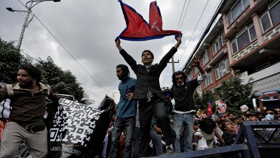 Smoke billows from an ambulance next to riot police officers and demonstrators during a protest against corruption and the government’s decision to block several social media platforms, in Kathmandu, Nepal September 8, 2025. REUTERS/Stringer