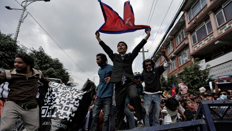 Smoke billows from an ambulance next to riot police officers and demonstrators during a protest against corruption and the government’s decision to block several social media platforms, in Kathmandu, Nepal September 8, 2025. REUTERS/Stringer