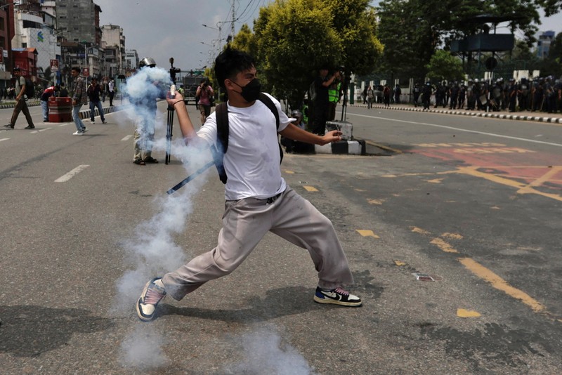 Smoke billows from an ambulance next to riot police officers and demonstrators during a protest against corruption and the government’s decision to block several social media platforms, in Kathmandu, Nepal September 8, 2025. REUTERS/Stringer