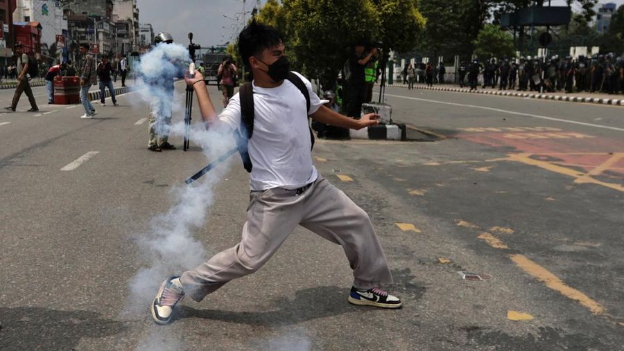 Smoke billows from an ambulance next to riot police officers and demonstrators during a protest against corruption and the government’s decision to block several social media platforms, in Kathmandu, Nepal September 8, 2025. REUTERS/Stringer